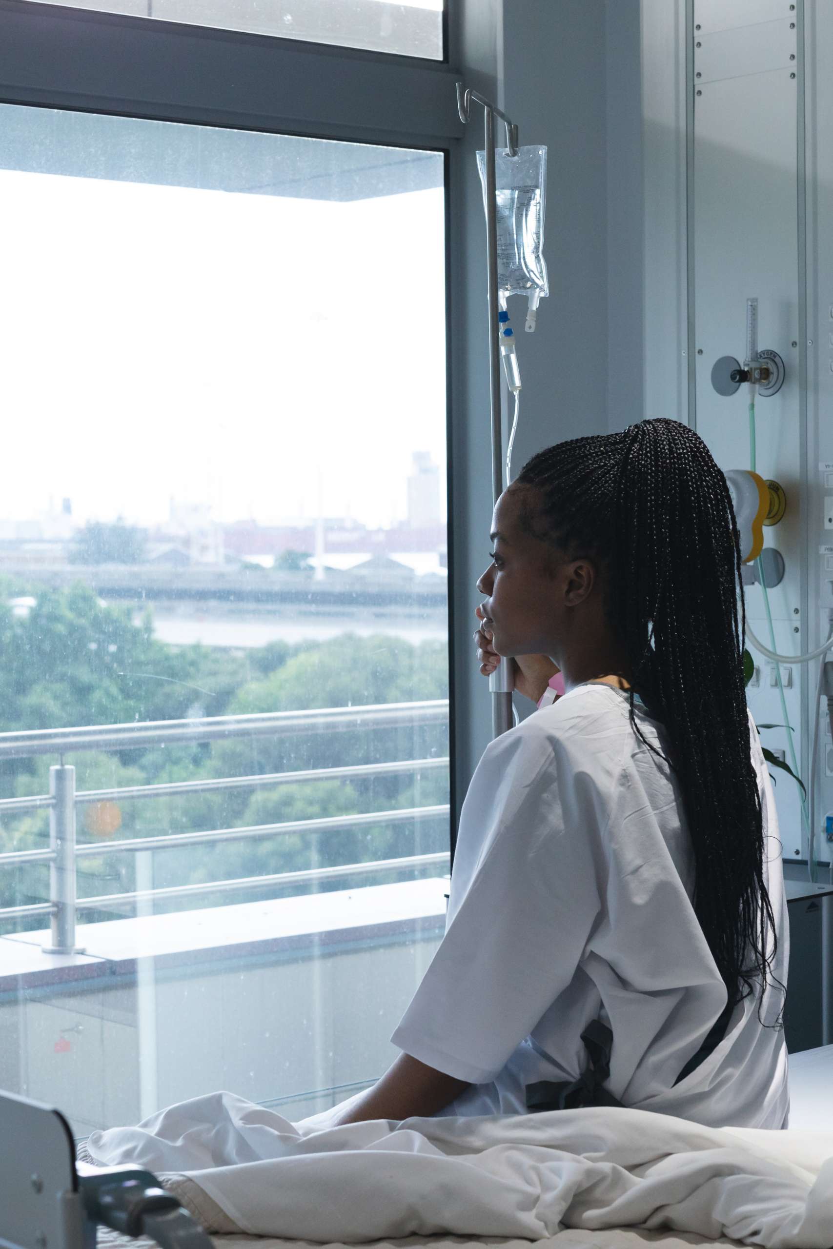 Teenager hospital patient looking out window waiting for help