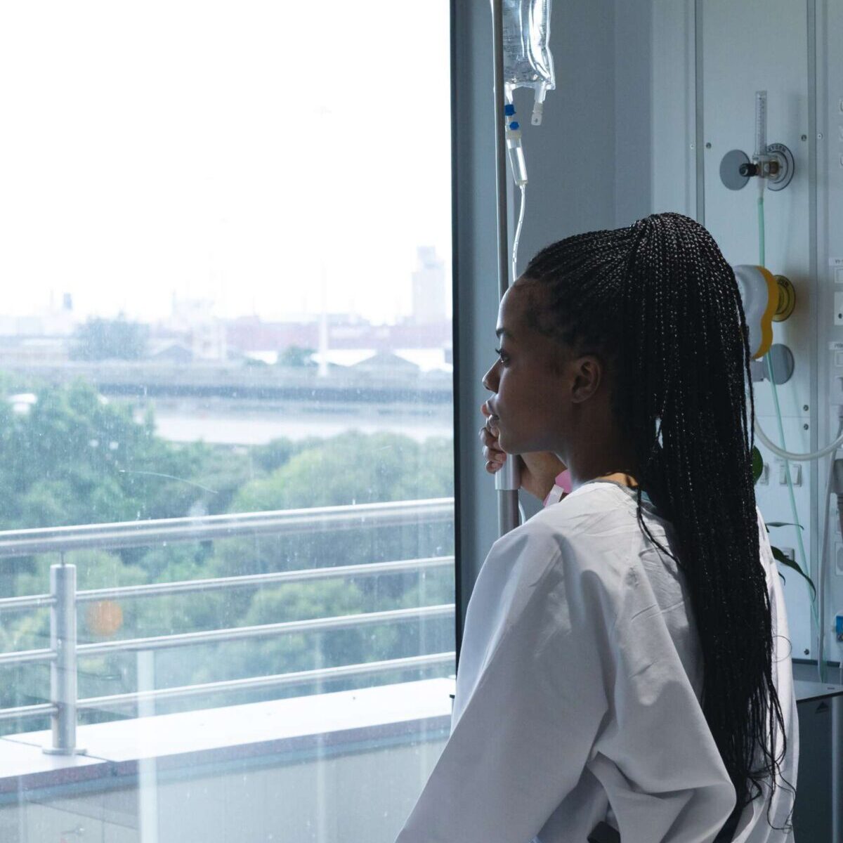 Teenager hospital patient looking out window Teenager hospital patient looking out window waiting for help